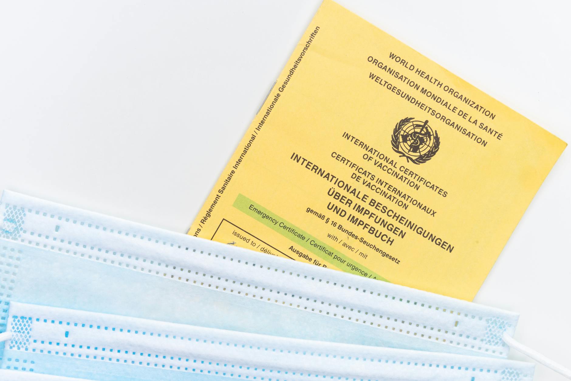 An international vaccination certificate with face masks on a white surface symbolizing health safety.
